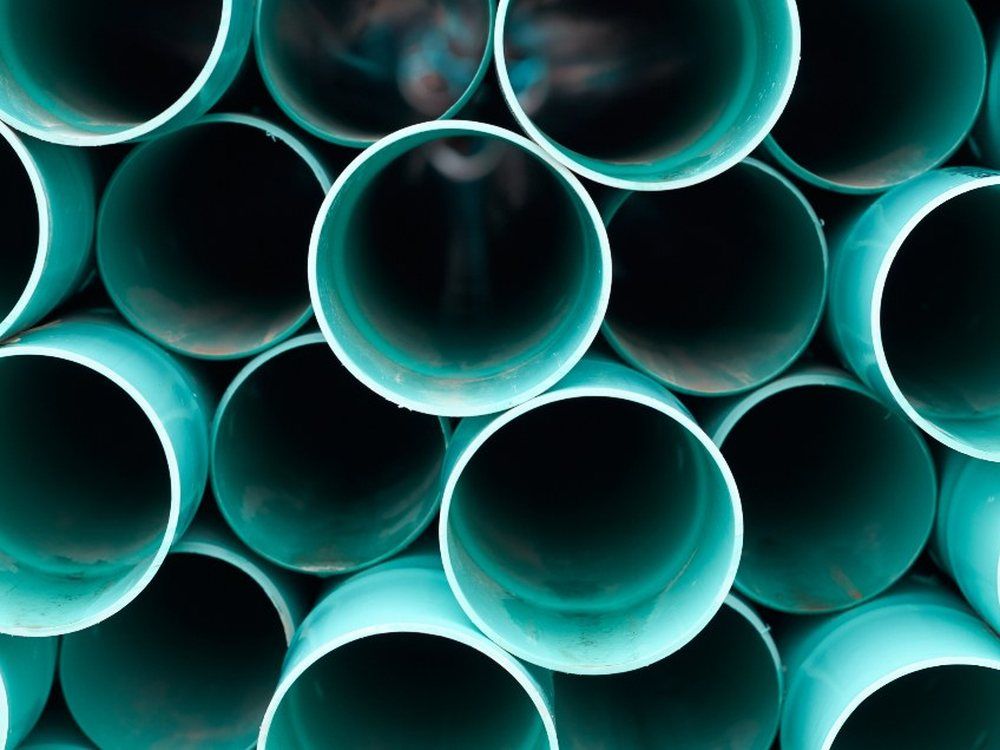The open ends of a stack of teal plastic drainage pipes