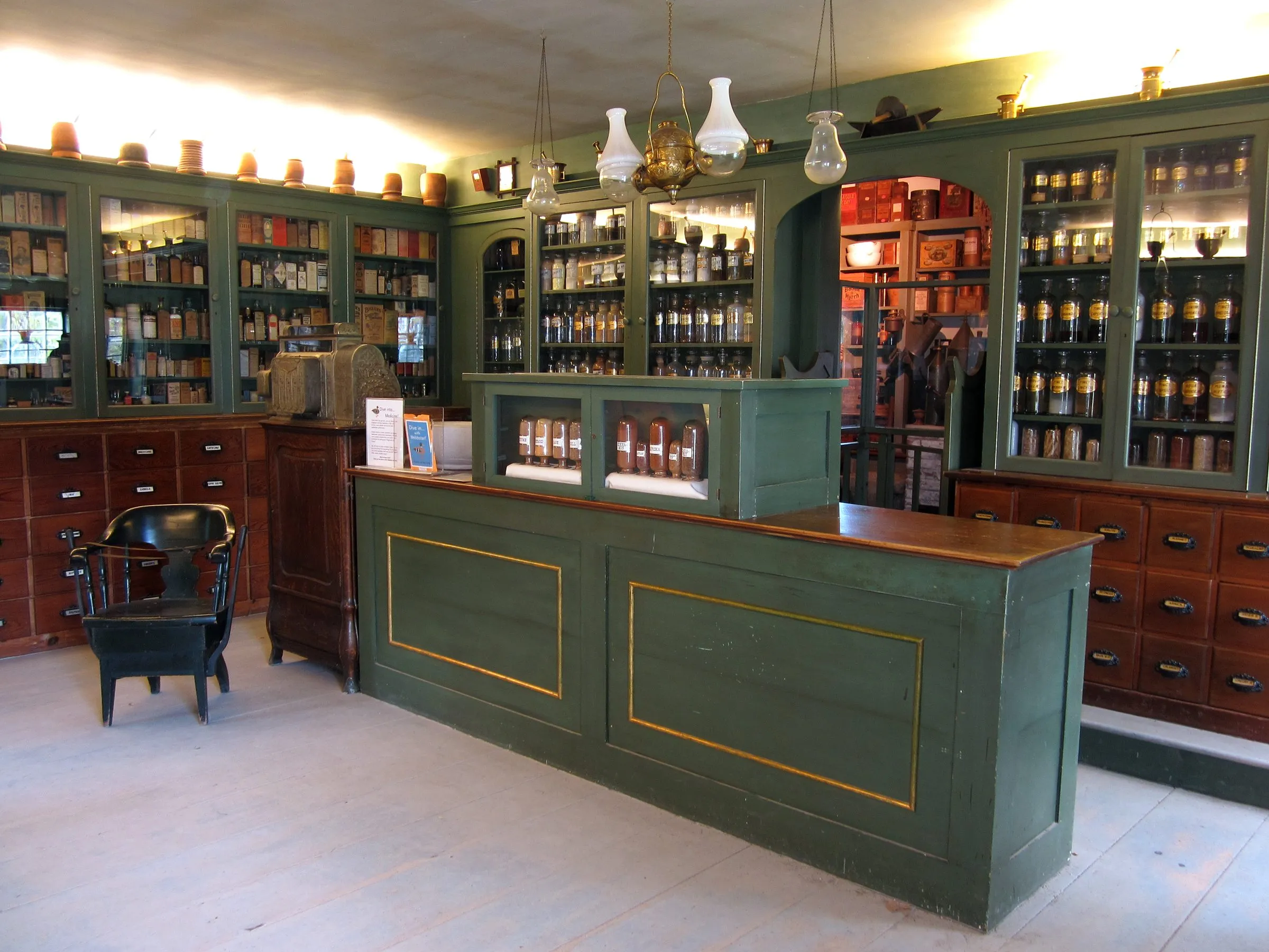 The interior of a small independent shop, with green cabinetry, glass-fronted shelves and a wooden counter